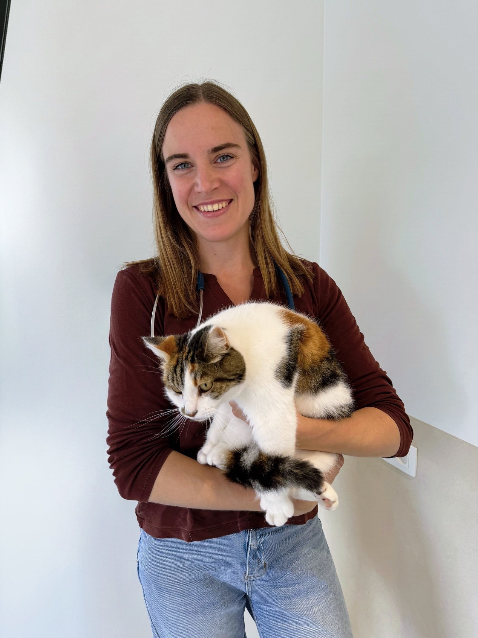 Jana Vermeiren, dierenarts, met een stethoscoop om haar nek en een kat in haar armen